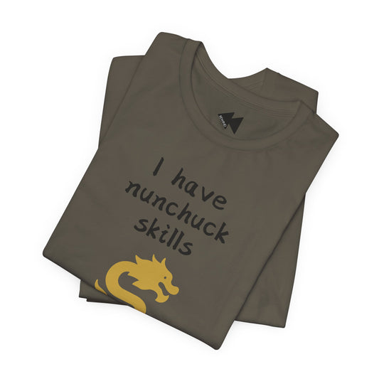 A folded dark olive green t-shirt with the text 'I have nunchuck skills' in black and a yellow nunchuck graphic, displayed on a clean white background.
