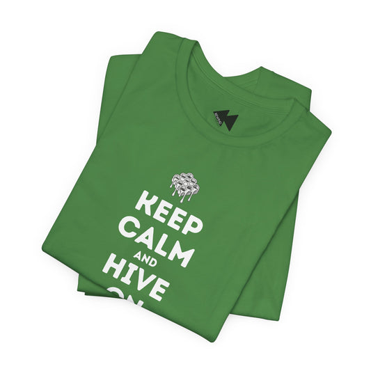 A folded green t-shirt with a white graphic print that reads 'KEEP CALM AND HIVE ON' below a dripping bee design, displayed on a clean white background.