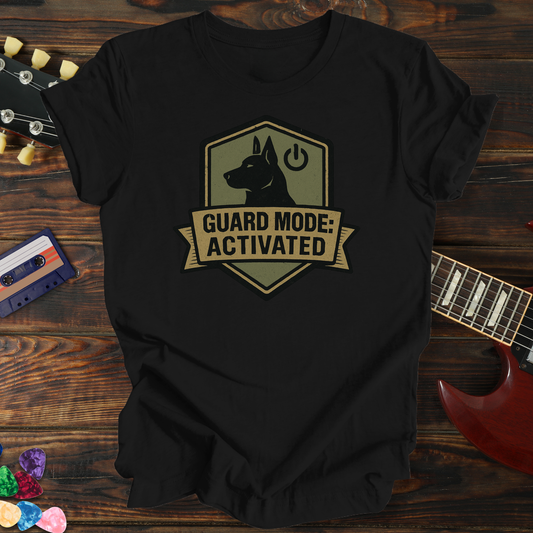 Black t-shirt with 'Guard Mode: Activated' graphic on a wooden surface with guitar and cassette tape.