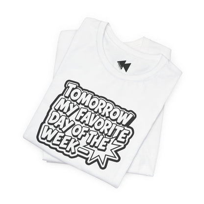 A folded white short-sleeve T-shirt with a bold black and white graphic reading 'TOMORROW MY FAVORITE DAY OF THE WEEK' on the front, shown on a clean white background.