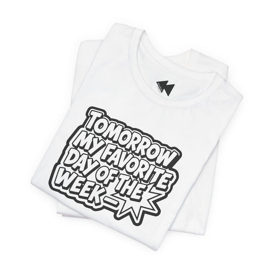A folded white short-sleeve T-shirt with a bold black and white graphic reading 'TOMORROW MY FAVORITE DAY OF THE WEEK' on the front, shown on a clean white background.