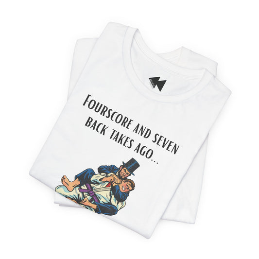 A folded white t-shirt with a black graphic print that reads 'Fourscore and Seven Back Takes Ago.
