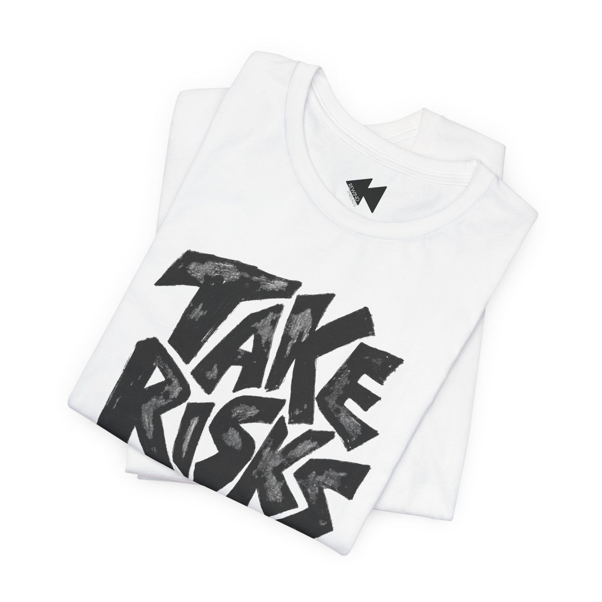 A folded white t-shirt with a large black graphic print reading 'TAKE RISKS' in a bold, hand-drawn style. A small black lightning bolt logo is visible inside the collar.
