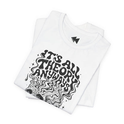 A folded white t-shirt with a black graphic print that reads 'IT'S ALL THEORY ANYWAYS' in a stylized, wavy font. A small black geometric logo is visible inside the collar.