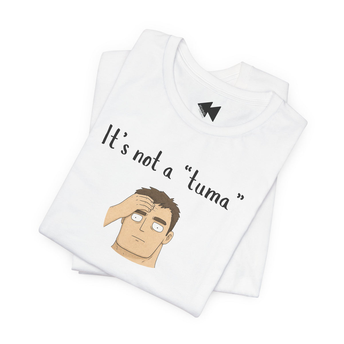 A folded white t-shirt with a graphic print that reads 'It's not a "tuma"' above an illustration of a man with brown hair covering his face. The shirt features a black geometric logo inside the collar.
