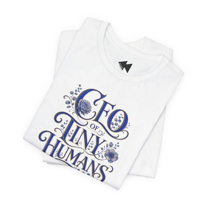 A folded white t-shirt with a blue graphic print that reads 'CEO of TINY HUMANS' in an ornate script with floral details, set against a plain white background.