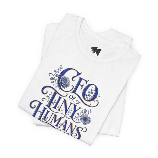 A folded white t-shirt with a blue graphic print that reads 'CEO of TINY HUMANS' in an ornate script with floral details, set against a plain white background.