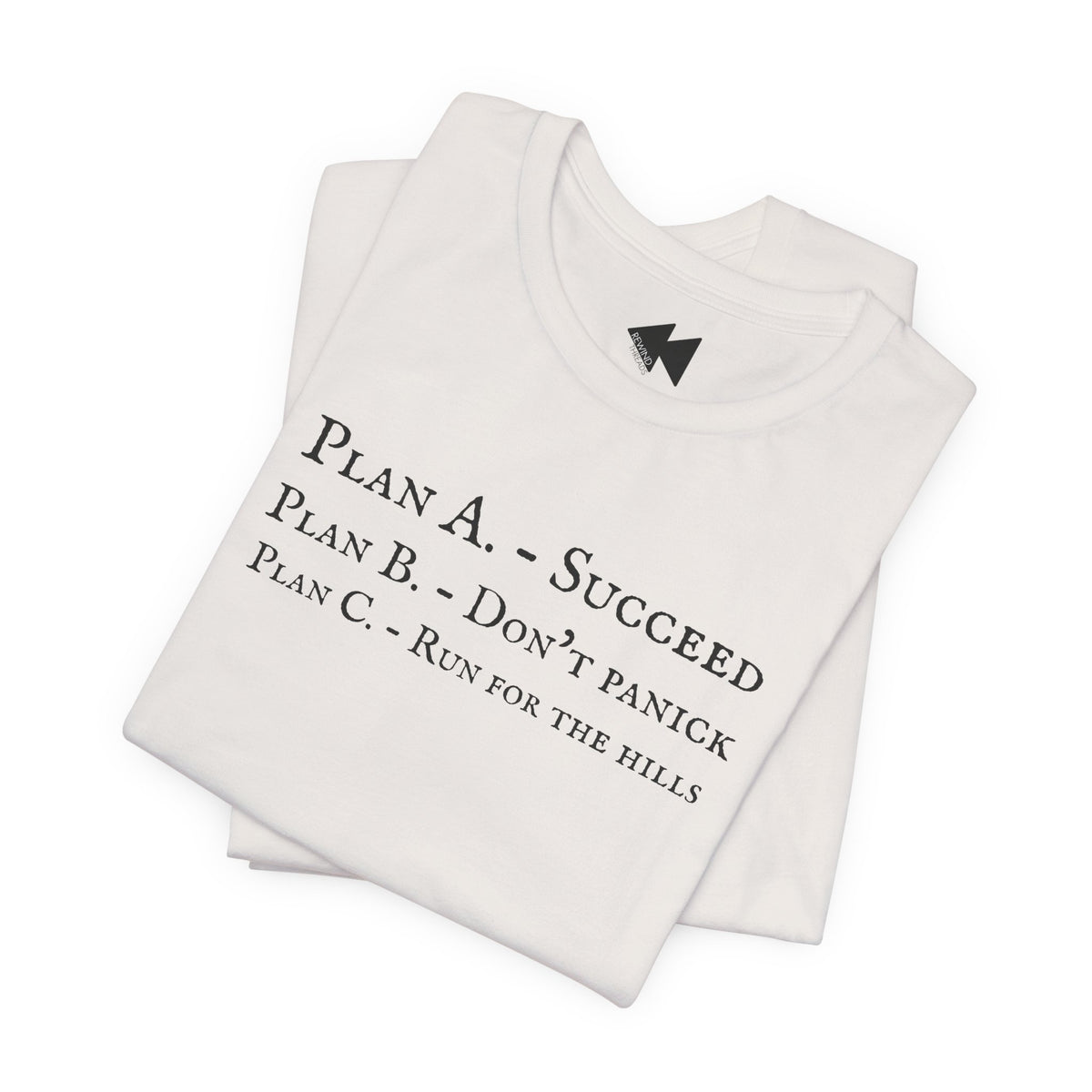 A folded light beige short-sleeve crewneck t-shirt with black printed text on the front reading 'PLAN A. - SUCCEED PLAN B. - DON'T PANICK PLAN C. RUN FOR THE HILLS'