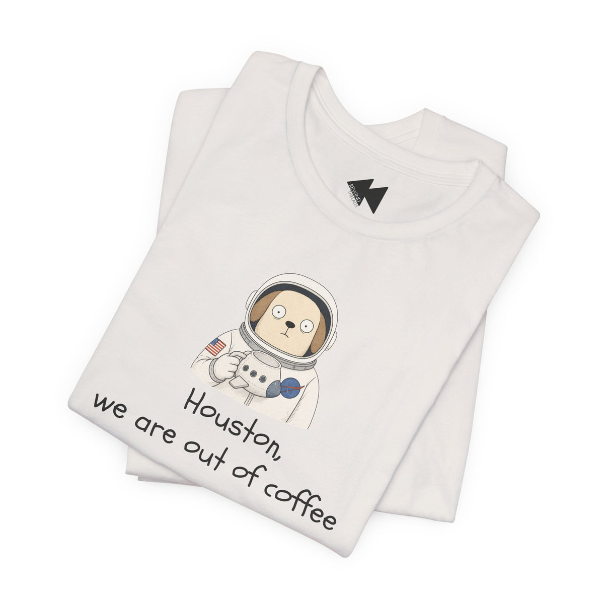 A folded light beige t-shirt with a cartoon astronaut dog graphic and the text 'Houston, we are out of coffee' printed on the front, displayed on a clean white background.