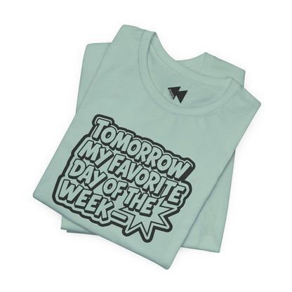 A folded mint green t-shirt with a bold black and white graphic reading 'TOMORROW MY FAVORITE DAY OF THE WEEK' on a clean white background.