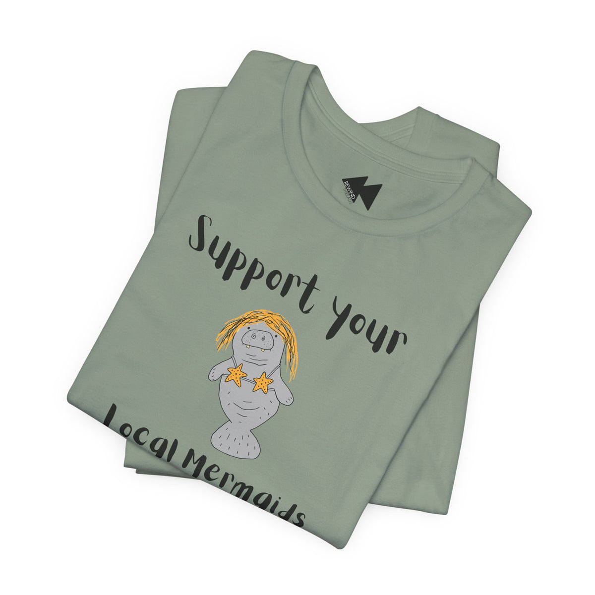 A folded sage green t-shirt with a graphic of a mermaid manatee and the text 'Support your Local Mermaids' in black script, displayed on a clean white background.