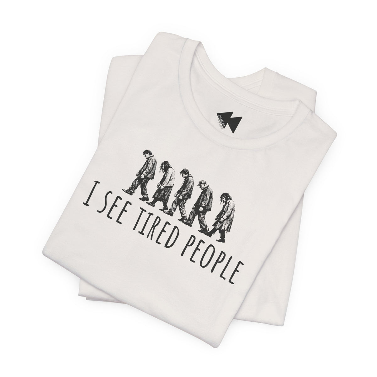 A folded white t-shirt with a black graphic print showing the evolution of humans walking and the text 'I SEE TIRED PEOPLE'. A small black geometric logo is printed inside the collar.