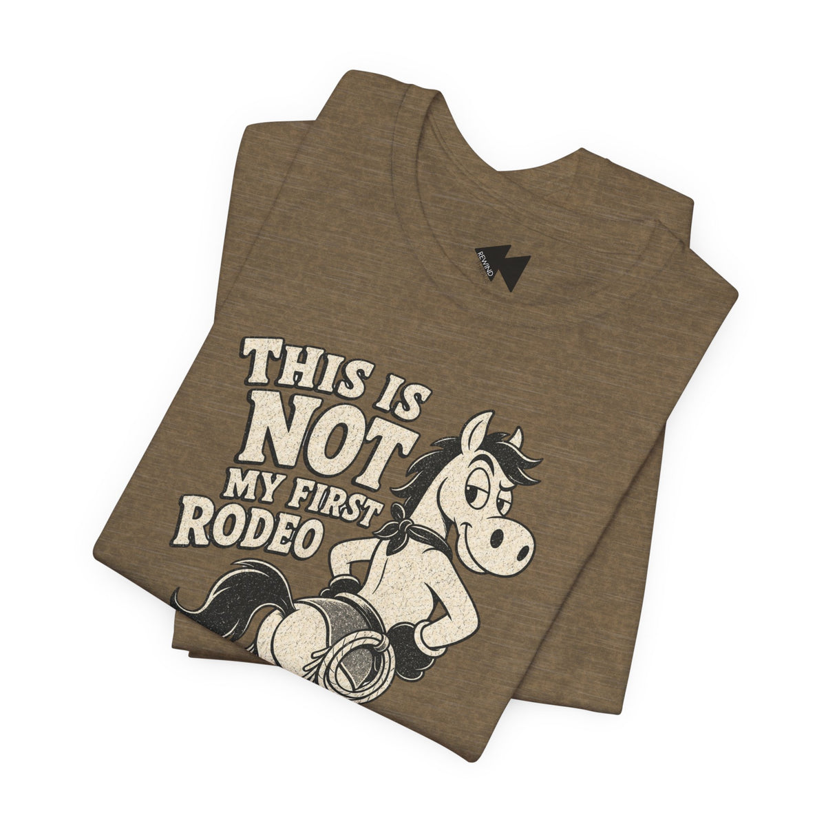 A folded brown heather t-shirt featuring a graphic print of a cartoon horse wearing a cowboy hat and bandana, with the text 'THIS IS NOT MY FIRST RODEO' in a distressed cream font.