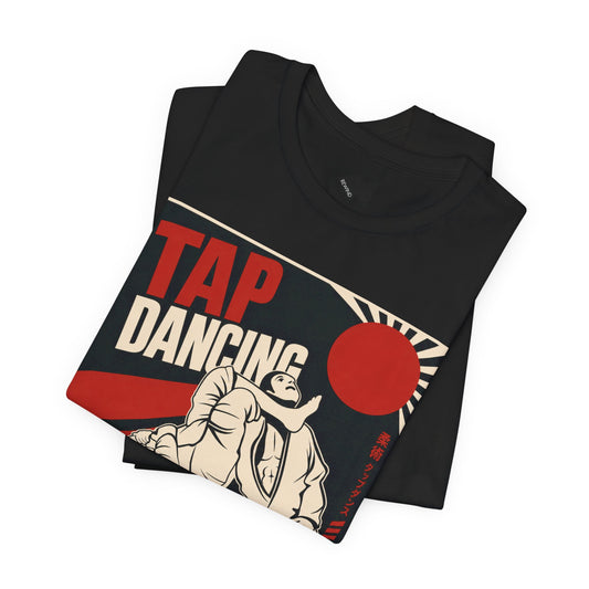 A folded black T-shirt with a vintage-style 'TAP DANCING' graphic in red, white, and beige, featuring an illustration of two BJJ fighters and a rising sun, shown on a plain white background.