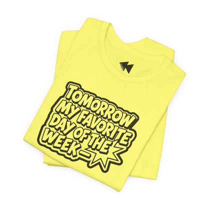 A folded bright yellow t-shirt with a black graphic text reading 'TOMORROW MY FAVORITE DAY OF THE WEEK' on a white background.