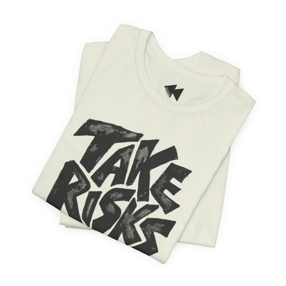 A folded off-white t-shirt with a large black graphic reading 'TAKE RISKS' in a bold, hand-drawn style font, displayed on a clean white background.