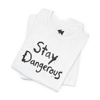 A folded white t-shirt with the words 'Stay Dangerous' printed in a black distressed brush font on the front, displayed on a clean white background.
