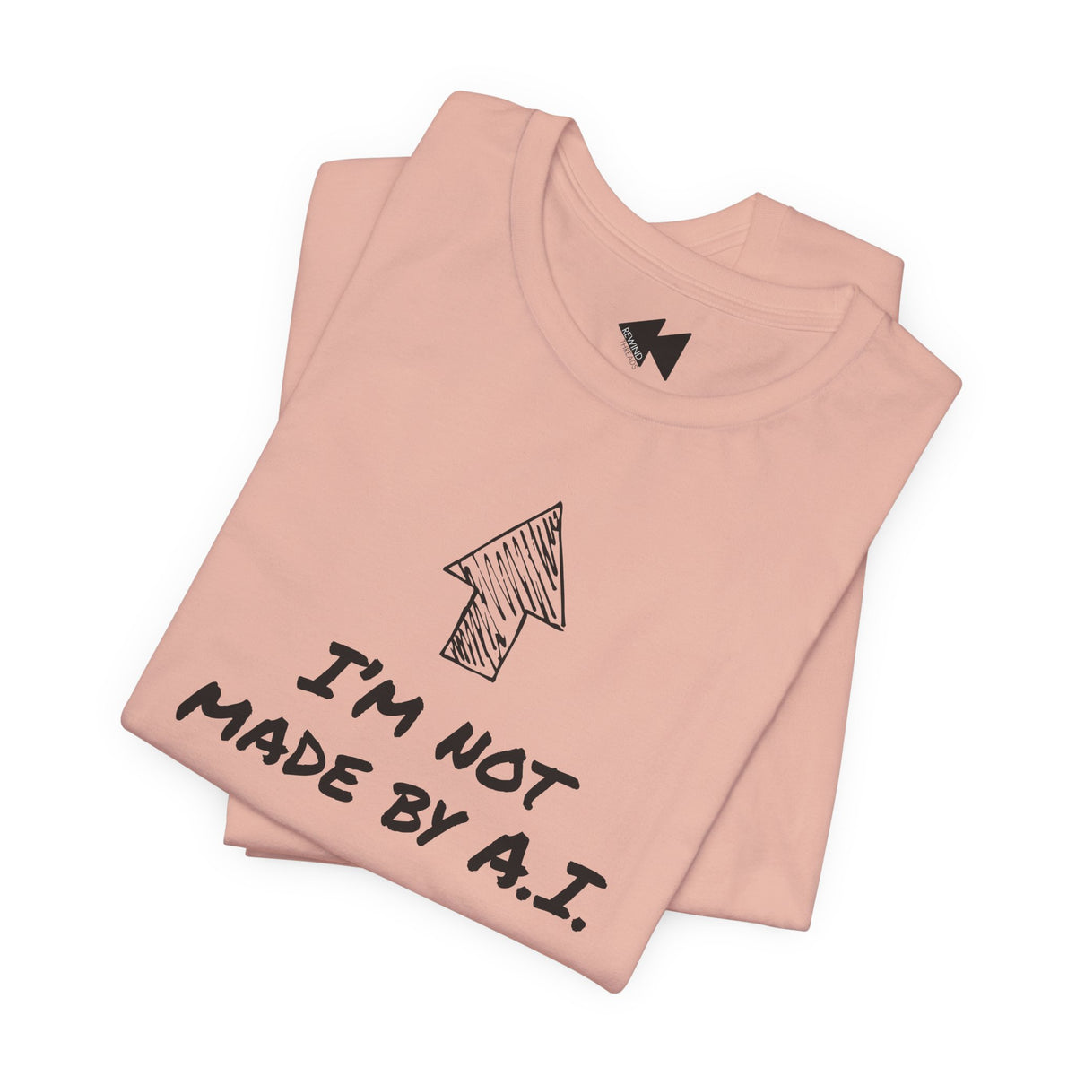 A folded light peach t-shirt with a black hand-drawn arrow graphic and the text 'I'M NOT MADE BY A.I.