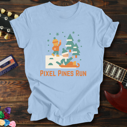 Light blue t-shirt with 'Pixel Pines Run' graphic on a wooden surface with a guitar and colorful objects.