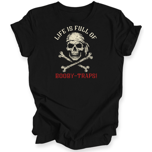 A black short-sleeve t-shirt with a distressed pirate-themed graphic on the front. The design features a skull wearing a bandana above crossed bones, with the text 'LIFE IS FULL OF' in white arched above and 'BOOBY-TRAPS!' in red below.