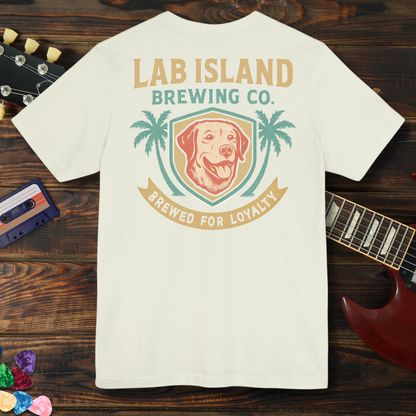 White t-shirt with Lab Island Brewing Co. logo on a wooden surface with a guitar and cassette tape.