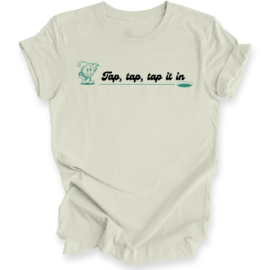 An off-white short-sleeve t-shirt with a graphic on the chest that reads 'Tap, tap, tap it in' in black script with a teal  outline and a small teal character. The shirt is shown against a plain white background with soft drop shadows.