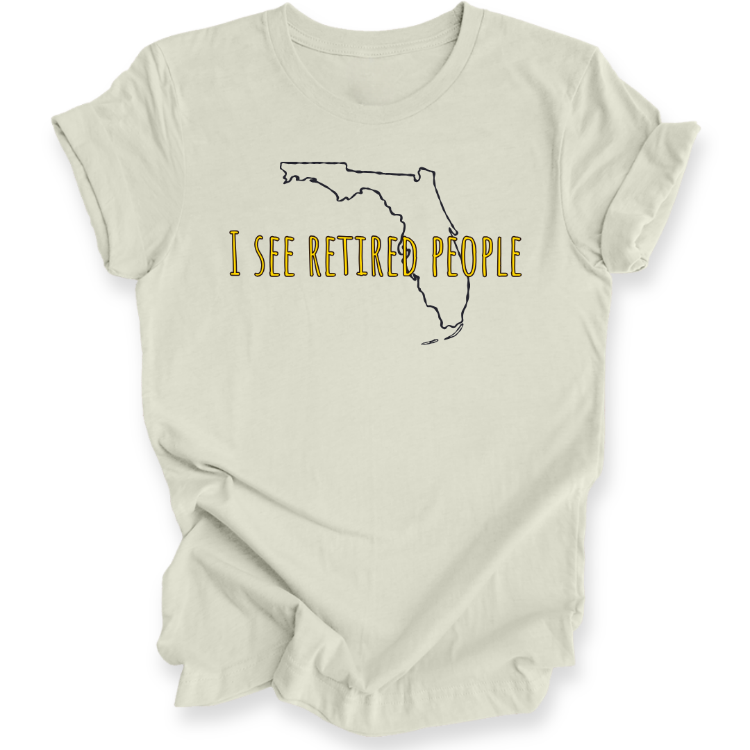 A citron green short-sleeve crewneck t-shirt with a graphic of the state outline of Florida in black, with the text 'I SEE RETIRED PEOPLE' written across it in a textured gold font.