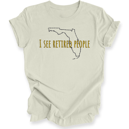 A citron green short-sleeve crewneck t-shirt with a graphic of the state outline of Florida in black, with the text 'I SEE RETIRED PEOPLE' written across it in a textured gold font.