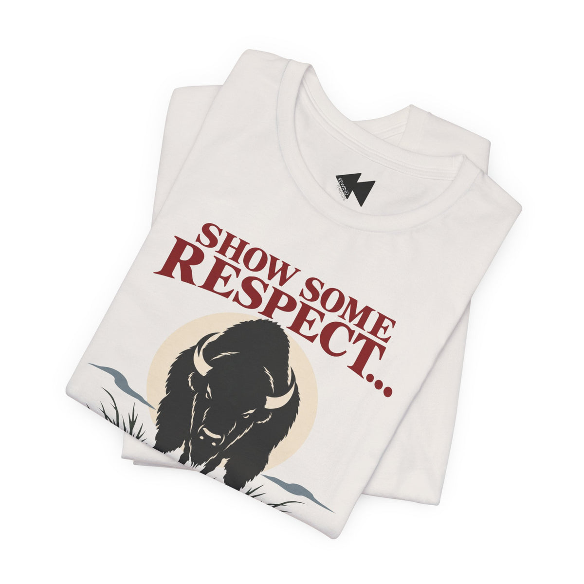 A folded white t-shirt  featuring a black bison illustration and the text 'SHOW SOME RESPECT I'M LAKOTA