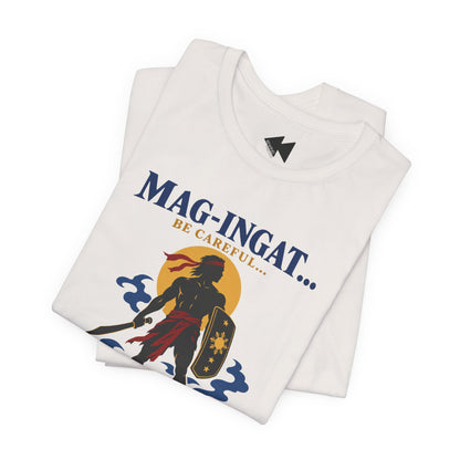 A folded white t-shirt with a graphic print featuring a samurai warrior silhouette, a yellow sun, blue waves, and the text 'MAG-INGAT.