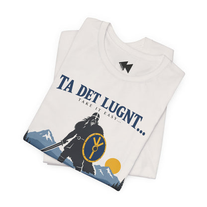 A folded white t-shirt with a graphic print of a Viking warrior, mountains, and the text 'TA DET LUGNT.
