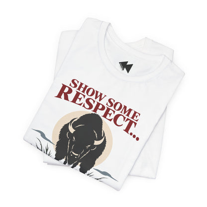 A folded white t-shirt  featuring a black bison illustration and the text 'SHOW SOME RESPECT I'M LAKOTA