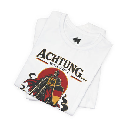A folded white t-shirt with a graphic print of a knight in armor and the German text 'Achtung.