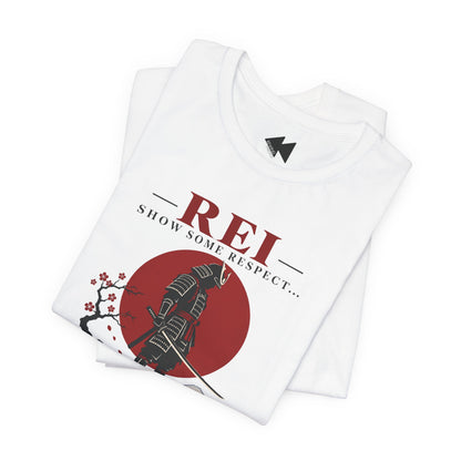 A folded white t-shirt with a graphic print featuring a samurai, a red sun, cherry blossoms, and the text 'REI SHOW SOME RESPECT.