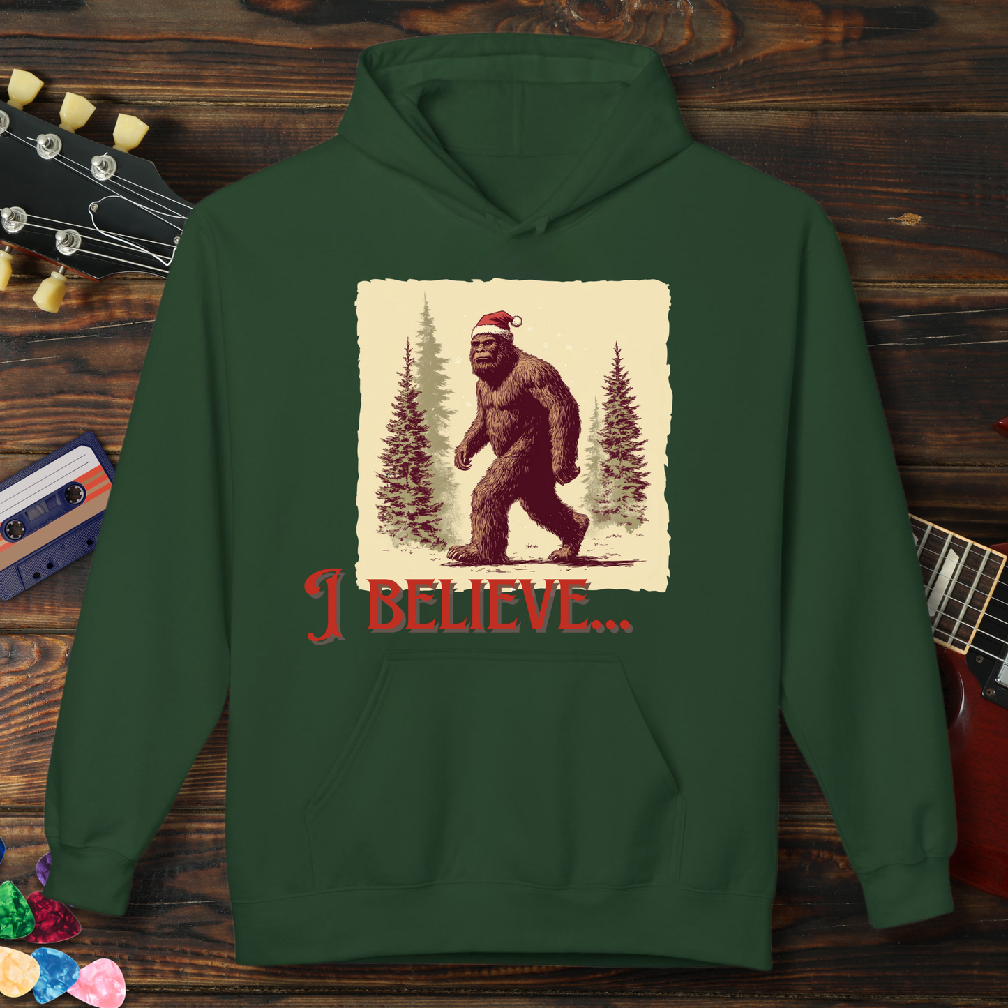 Green hoodie with a Bigfoot graphic and 'I Believe' text on a wooden background