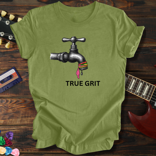 Green t-shirt with a tap graphic and 'True Grit' text on a wooden surface with a guitar and cassette tape.