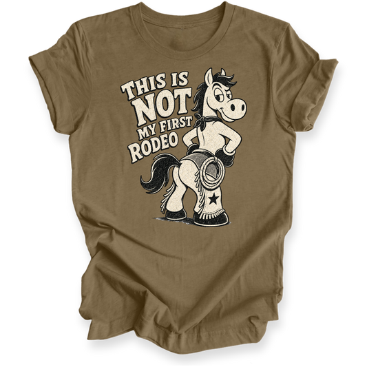 A brown short-sleeve t-shirt with a graphic print of a cartoon horse wearing cowboy boots and the text 'THIS IS NOT MY FIRST RODEO'.