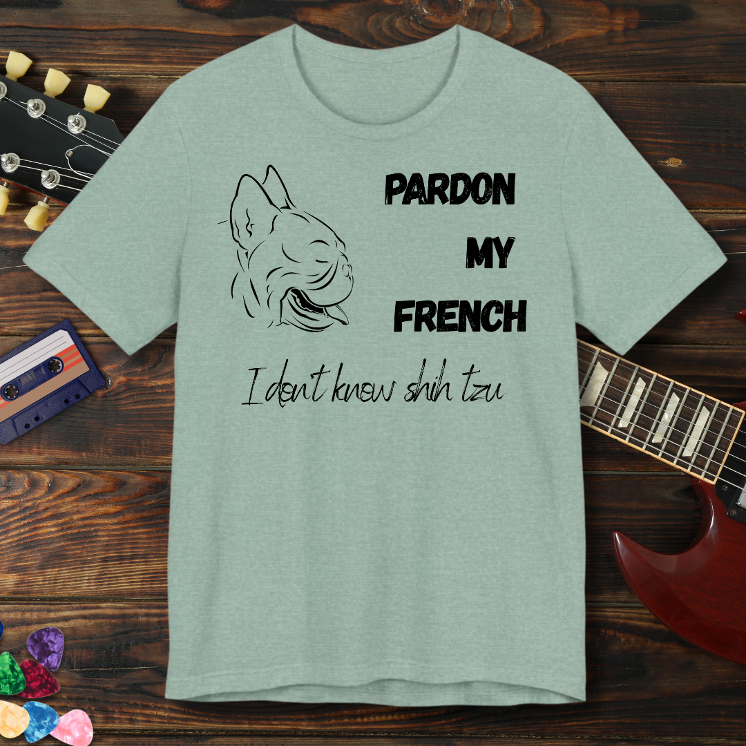 Green t-shirt with dog graphic and text on a wooden surface with a guitar and cassette tape.