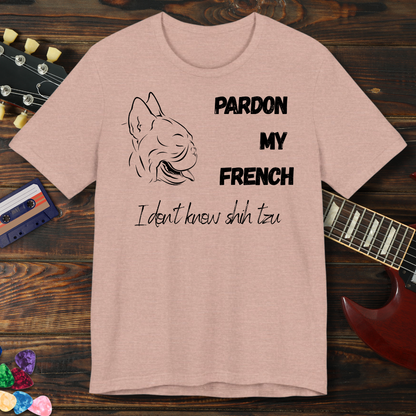 Beige t-shirt with dog illustration and text on a wooden surface with a guitar and cassette tape.