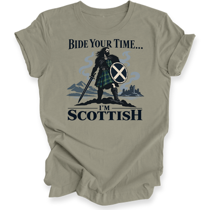 A taupe-colored short-sleeve t-shirt with a graphic of a Scottish warrior holding a sword and shield, with the text 'BIDE YOUR TIME.