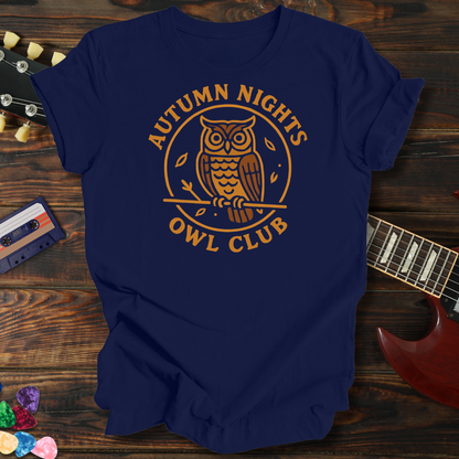 Navy blue t-shirt with 'Autumn Nights Owl Club' design on a wooden surface with a guitar and cassette tape.