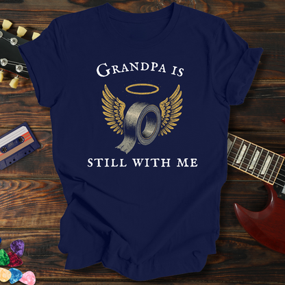 Navy blue t-shirt with 'Grandpa is still with me' graphic on a wooden surface with a guitar and cassette tape.