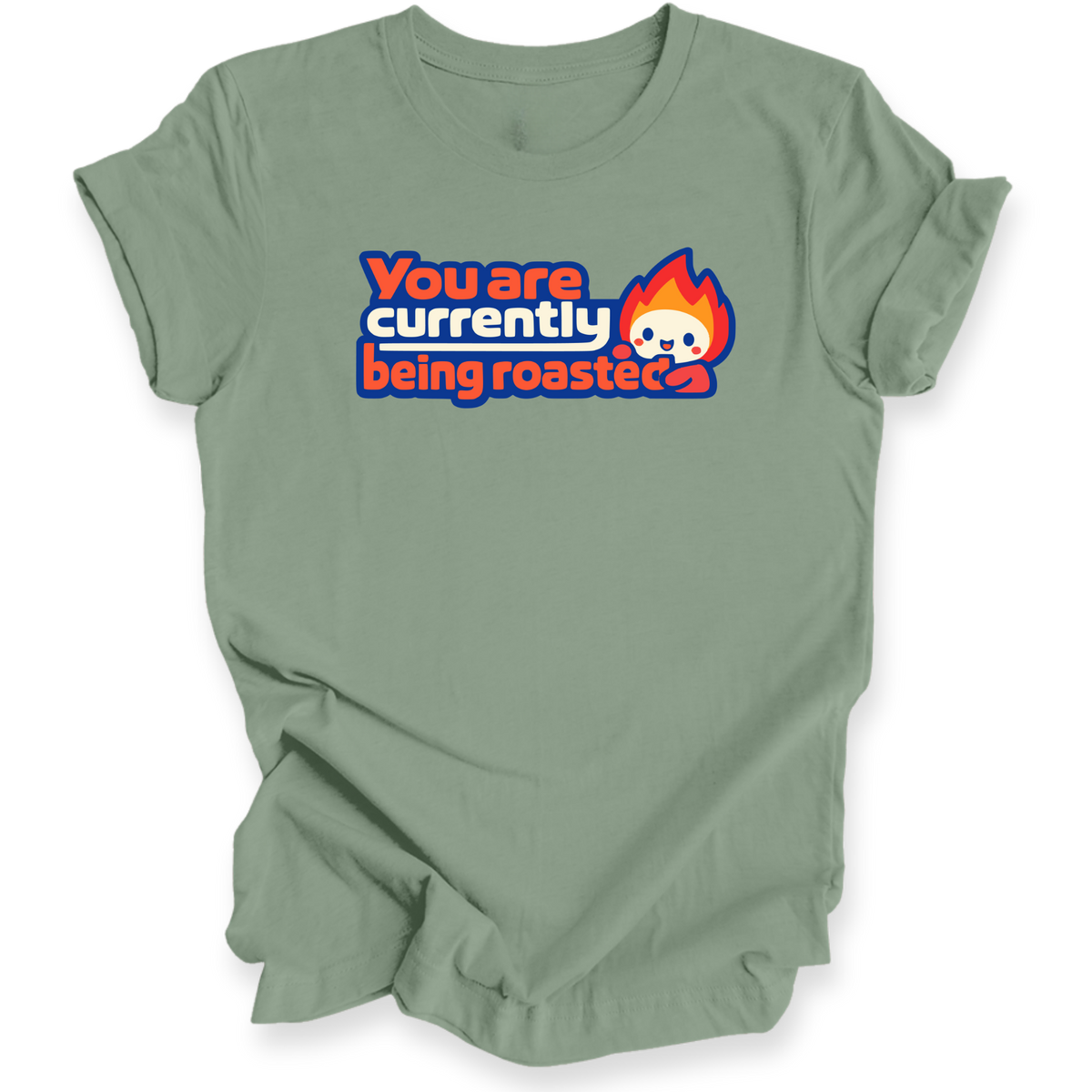 A sage green short-sleeve t-shirt with a graphic on the chest that reads 'You are currently being roasted' in white and orange text with a cartoon flame character, displayed on a clean white background.