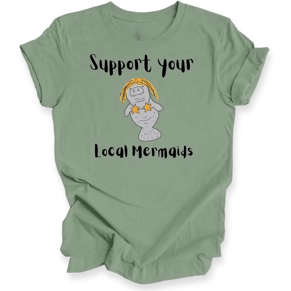 A sage green short-sleeve t-shirt with a graphic of a cartoon manatee wearing yellow hair and star earrings, with the text 'Support your Local Mermaids' printed in black.