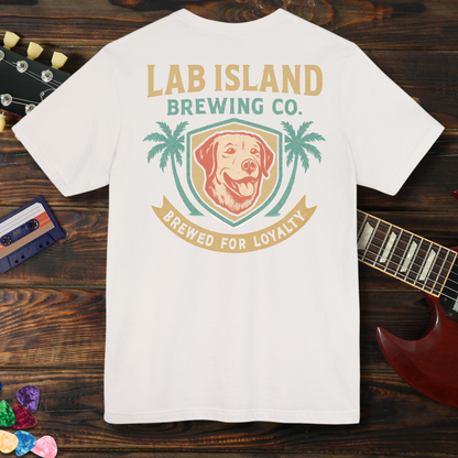 White t-shirt with Lab Island Brewing Co. logo on a wooden surface with a guitar and cassette tape.