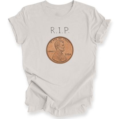 A light beige crewneck t-shirt with a graphic print of 'R.I.P.' with a penny.