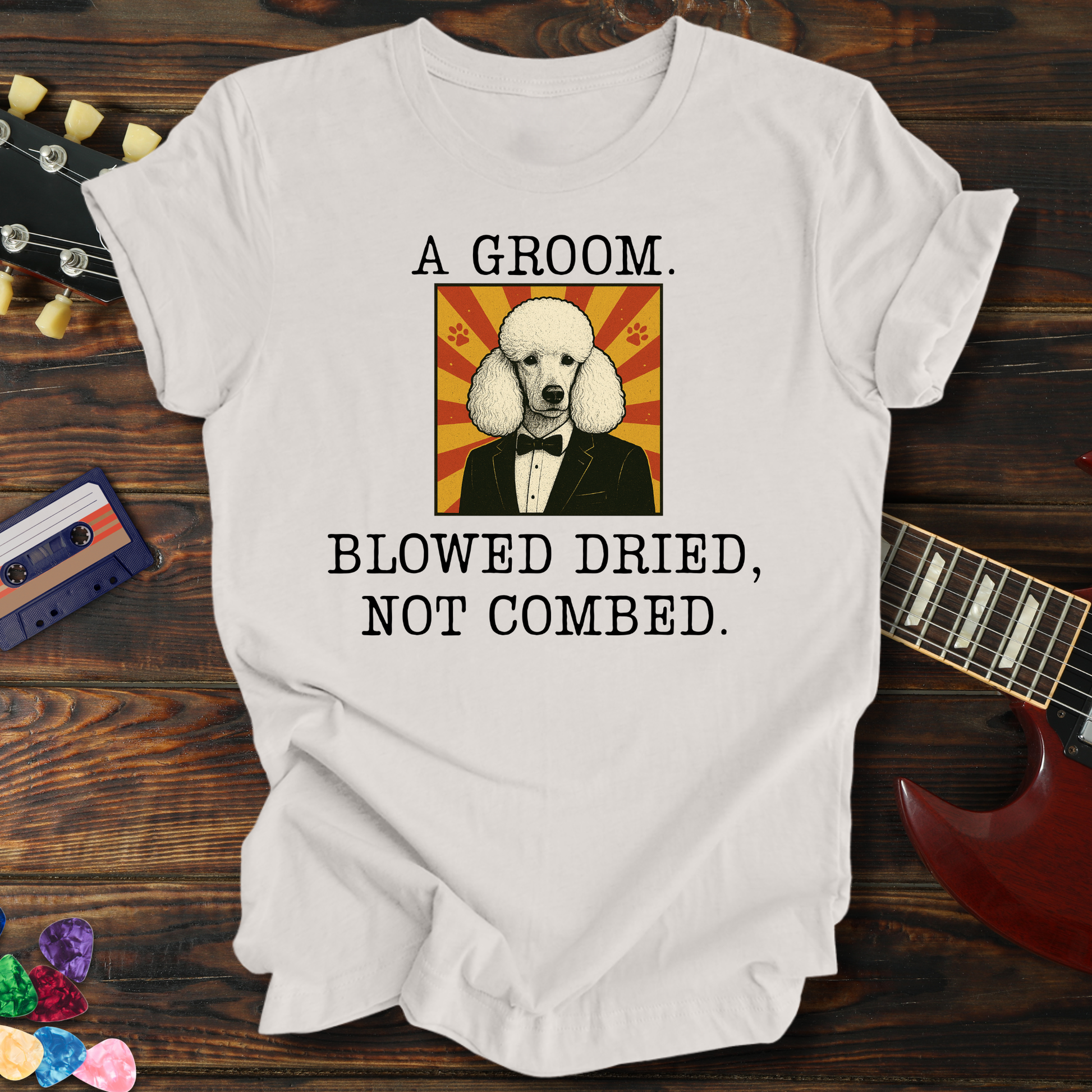White t-shirt with a graphic of a dog in a suit and text on a wooden surface with a guitar and cassette tape.