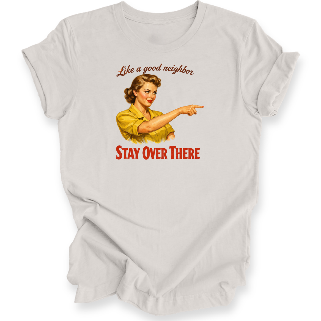 A light gray graphic t-shirt featuring a vintage-style illustration of a woman in a yellow shirt pointing, with the text 'Like a good neighbor' above and 'STAY OVER THERE' below in red.
