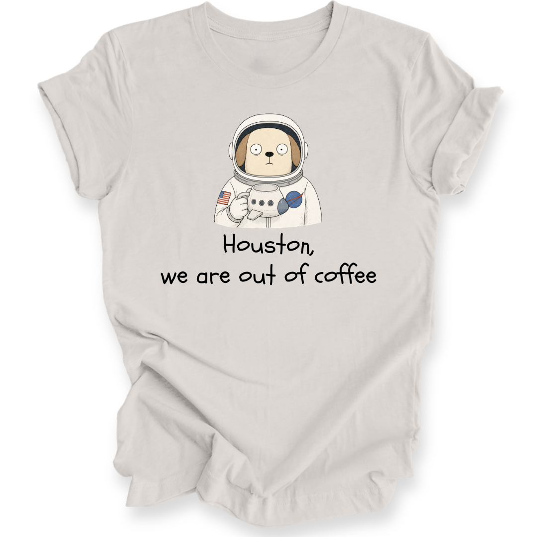 A light beige t-shirt with a cartoon astronaut dog graphic and the text 'Houston, we are out of coffee' printed on the front, displayed on a clean white background.