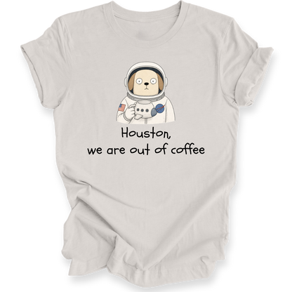 A light beige t-shirt with a cartoon astronaut dog graphic and the text 'Houston, we are out of coffee' printed on the front, displayed on a clean white background.